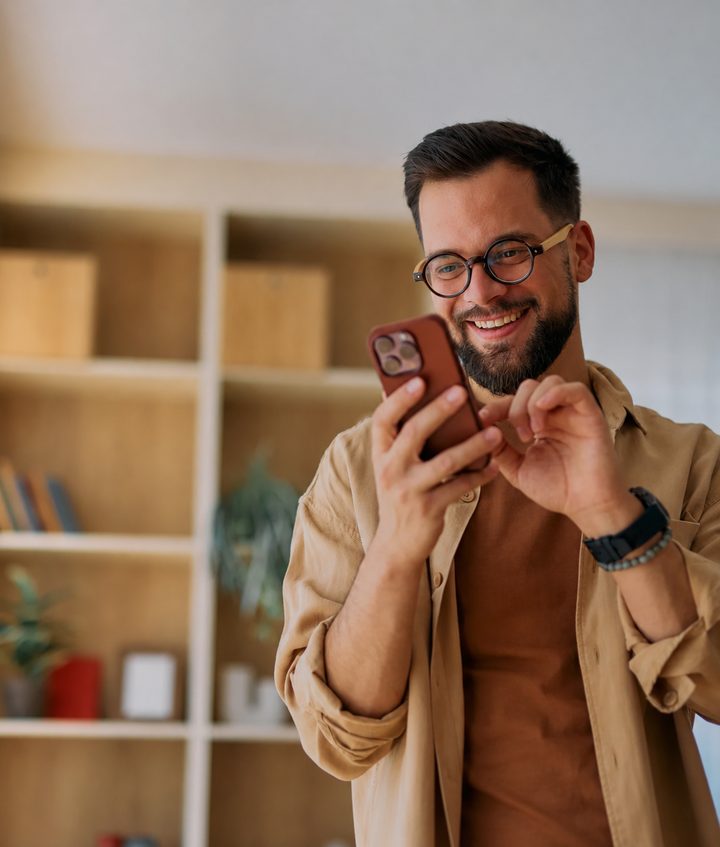 Smiling charter broker in glasses reviewing a charter request on his phone.